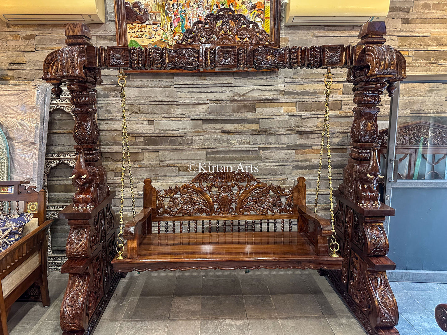 Carved wooden swing with intricate designs in a room setting.